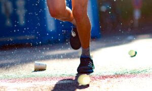 Corredores em prova de corrida de rua com copos descartáveis no percurso, representando a geração de resíduos em eventos esportivos