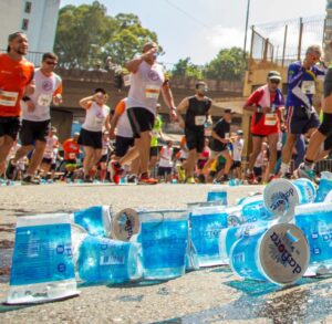 Corredores em prova de corrida de rua com copos plásticos descartados no chão durante o percurso